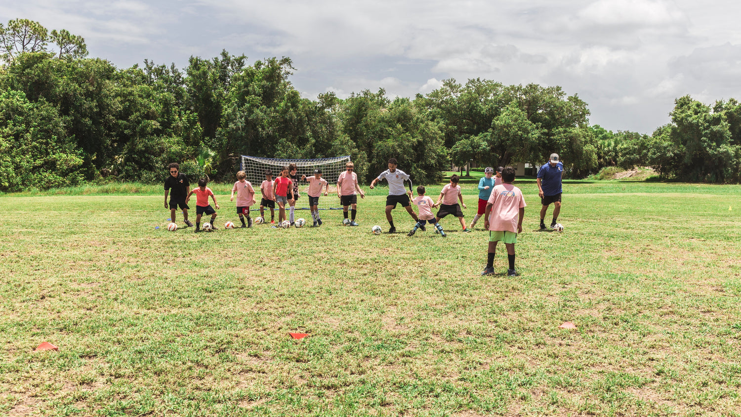 Group of people playing soccer on a grassy field with trees in the background